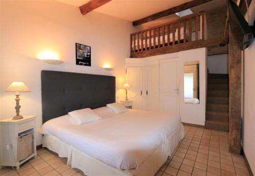 MeyralsにあるHôtel de la Ferme Lamyのベッドルーム1室(大きな白いベッド1台、階段付)