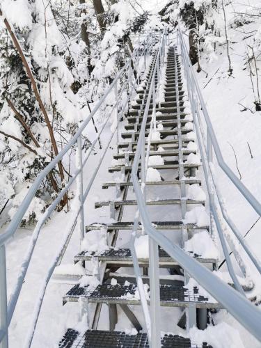 a metal bridge covered in snow with trees at Zamoček in Matiašovce