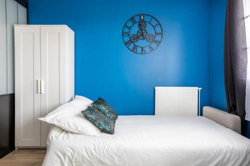 a blue bedroom with a white bed and a blue wall at Appartements proche Paris Disney in Torcy