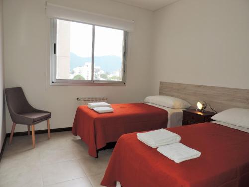 a room with two beds with red sheets and a window at Hanan Pacha - Apart Salta in Salta