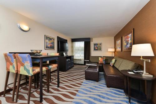a living room with a table and chairs in a hotel room at Holiday Inn Cody - Convention Center by IHG in Cody