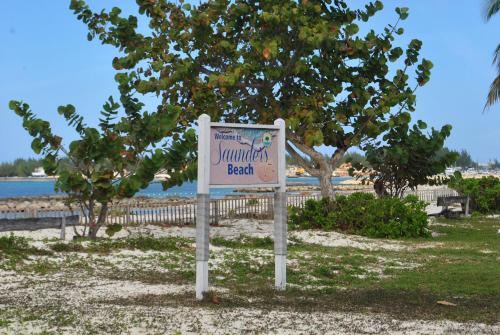 a sign on the beach in front of a tree at Tropical Hideaway in Nassau