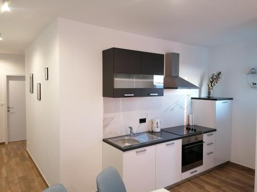 cocina con armarios blancos, fregadero y nevera en Apartments Jakov, en Makarska