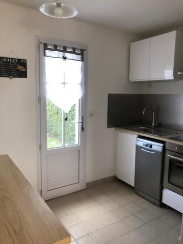- une cuisine avec une porte, un évier et une cuisinière dans l'établissement Maison Bord de Mer LE BIGORNEAU l'Herbaudière, à Noirmoutier-en-l'lle