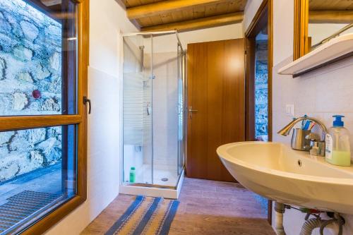 uma casa de banho com um lavatório e uma cabina de duche em vidro. em Le Casette di Laila em Colonno