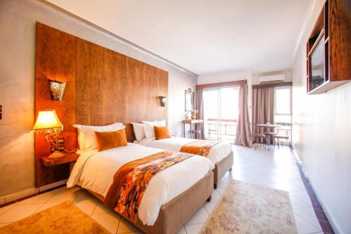 Habitación de hotel con 2 camas y mesa en Appart-Hotel EZZAHIA by HMS, en Marrakech