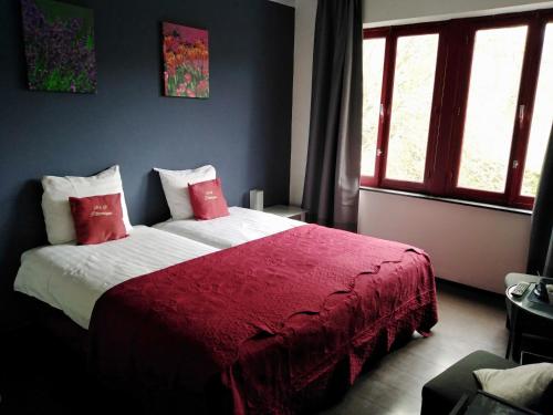 um quarto com uma cama grande e um cobertor vermelho em B&B Pittoresque em Houffalize