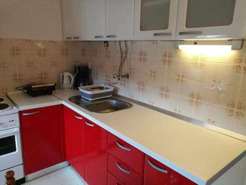 una cocina con armarios rojos y fregadero en Ivanka Apartments, en Vrboska