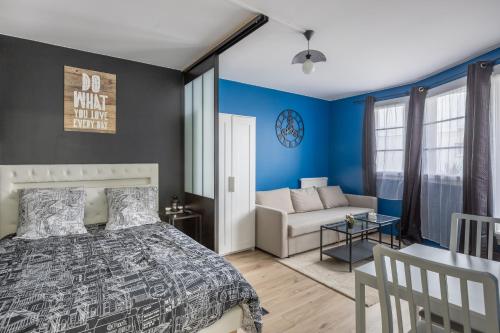 a bedroom with blue walls and a bed and a couch at Appartements proche Paris Disney in Torcy