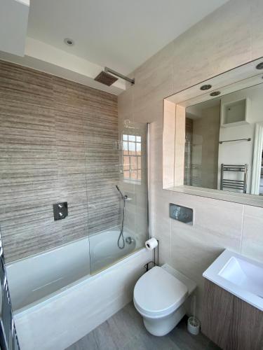 a bathroom with a toilet and a tub and a sink at CC - Central Location Top Floor 2 Bed Deluxe Modern Apartment in Stratford-upon-Avon