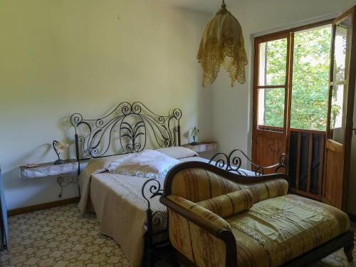 a bedroom with a bed and a chair and a window at Locanda SottoBosco in San Leonardo