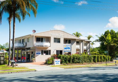 a white house sitting in front of a palm tree at Noosa Sun Motel in Noosaville