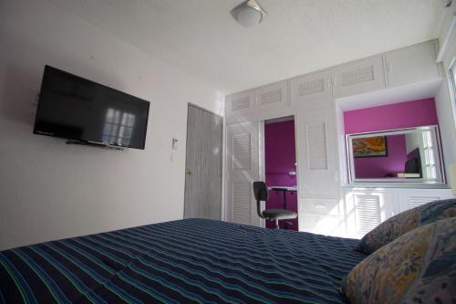 a hotel room with a bed and a flat screen tv at Casa Zac Nicte Mx-Habitacion IXCHEL in Cancún