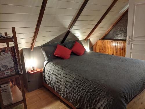 une chambre avec un lit avec deux oreillers rouges dans l'établissement Avel Nedeleg, à Coatreven