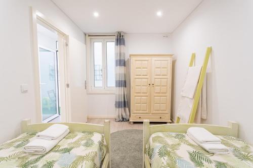 two beds in a room with a window at Luizinho House in Vila Nova de Gaia