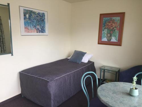 a bed in a room with a table and a picture at Bentons Motel in Levin