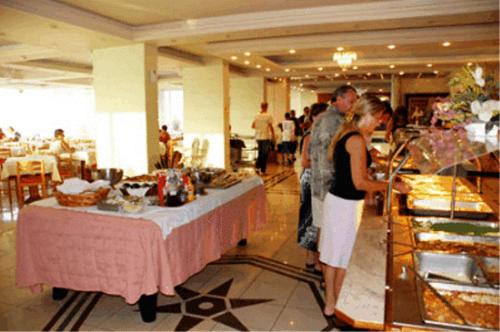a man and a woman standing in front of a buffet at Captains Hotel in Argassi