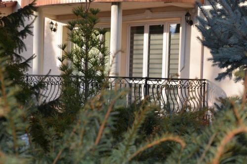 a white house with a black iron railing on a porch at Apartament DeLuxe 1 in Oświęcim