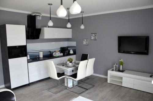 een woonkamer met een tafel en stoelen en een televisie bij Apartament DeLuxe 1 in Oświęcim