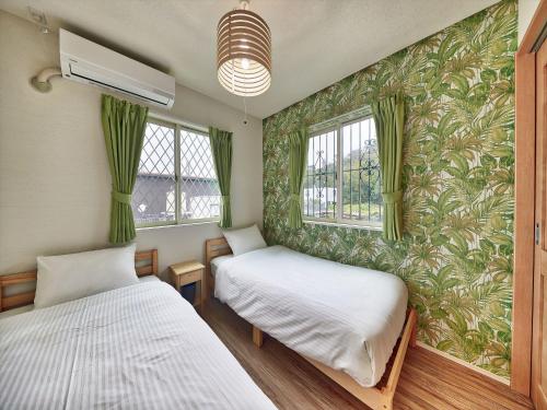 two beds in a room with green wallpaper at Private Villa Espacio Onna in Inbu