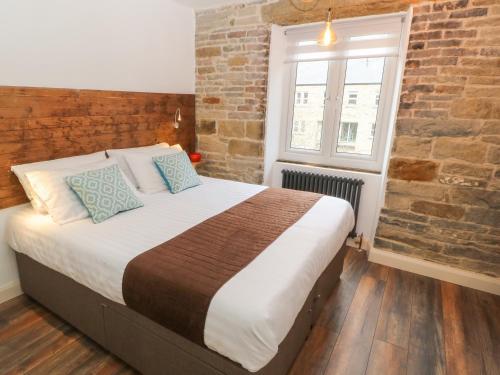 a bedroom with a large bed with a brick wall at Over-Under Cottage in Holmfirth