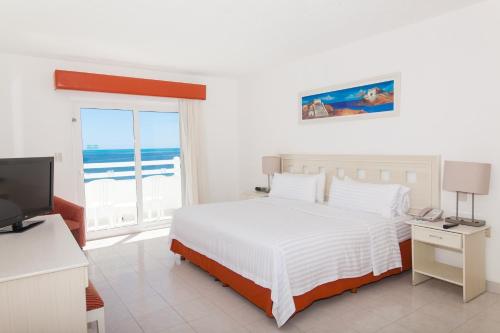 a white bedroom with a bed and a television at Ocean View Cancun Arenas in Cancún