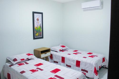 um quarto com duas camas com cobertores vermelhos e brancos em Pousada Residencial Milagre 02 em Juazeiro do Norte