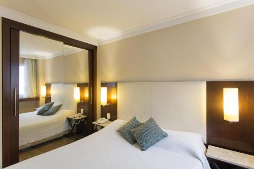 ein Hotelzimmer mit 2 Betten und einem Spiegel in der Unterkunft (1505)Flat Prime Paulista (Apt. particular) in São Paulo