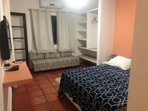 Dormitorio con cama, escritorio y TV en Pousada Kai en Itanhaém