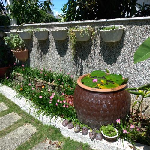 a flower garden with a large pot and some plants at Vineyard Guest House in Taitung City