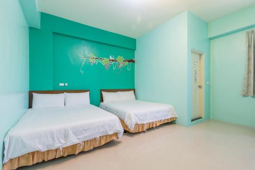 two beds in a room with a green wall at Vineyard Guest House in Taitung City