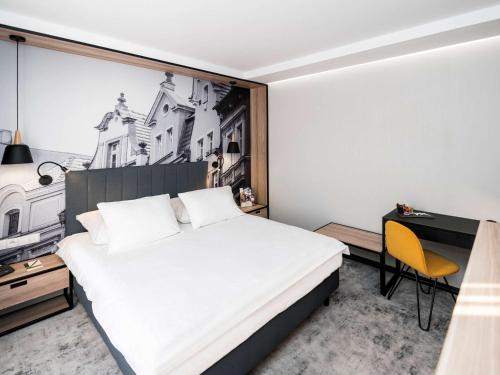 a bedroom with a bed and a desk and a chair at Mercure Jelenia Góra in Jelenia Góra