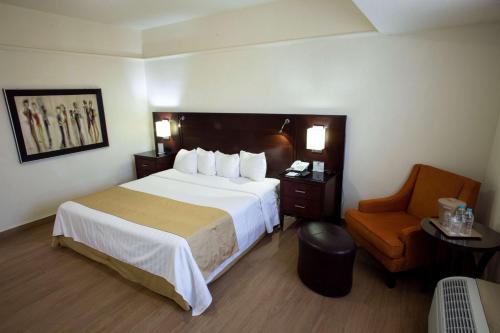 a hotel room with a large bed and a chair at Best Western Centro Monterrey in Monterrey