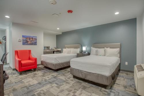 ein Hotelzimmer mit 2 Betten und einem roten Stuhl in der Unterkunft Post Time Inn in Carlsbad