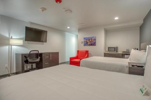 a hotel room with two beds and a red chair at Post Time Inn in Carlsbad