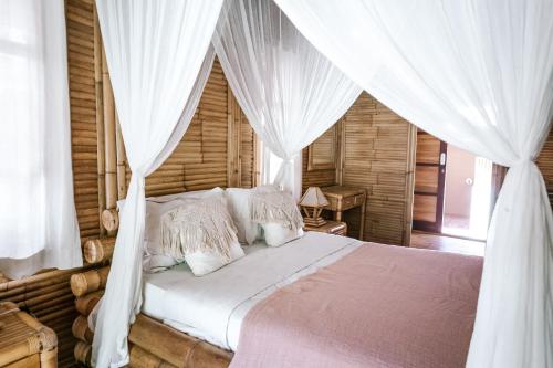 ein Schlafzimmer mit einem Himmelbett mit weißen Vorhängen in der Unterkunft Bamboo Bungalows in Nusa Lembongan