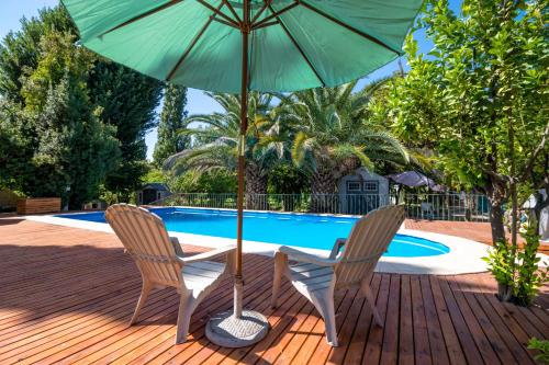 uma mesa e duas cadeiras com um guarda-sol ao lado de uma piscina em Quinta Ugarte em Luján de Cuyo