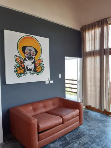 a brown leather couch in a room with a painting of a dog at Muyuyo Lodge in Ayangue