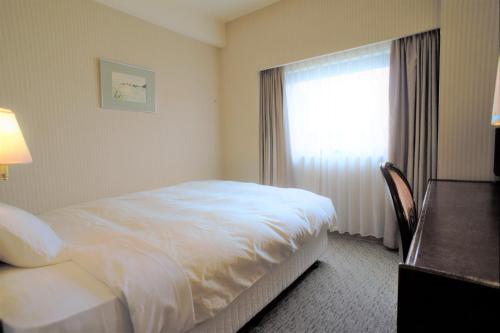 a hotel room with a bed and a window at Hotel Grand Terrace Toyama in Toyama