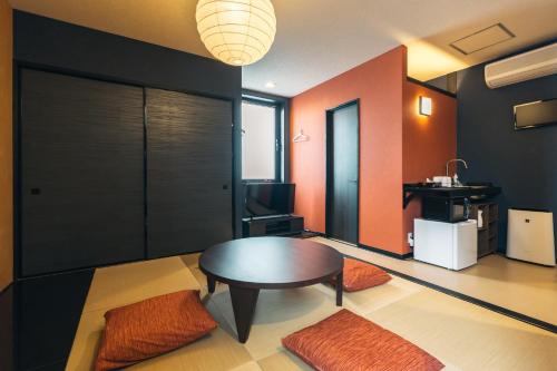 a living room with a table and a room with orange walls at KINGYO - Doyanen Hotels in Osaka