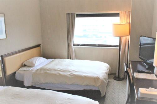 a hotel room with two beds and a window at Hotel Grand Terrace Toyama in Toyama