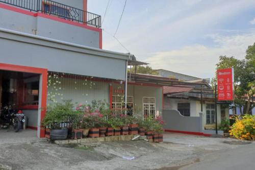 a building with flowers in pots outside of it at RedDoorz @ Hotel Yaki Mamuju in Rimuku
