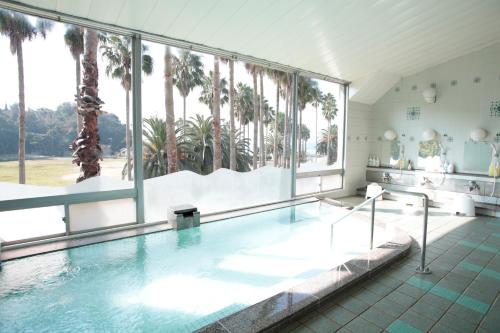 a swimming pool with a view of the palm trees at Kyukamura Ohkunoshima in Takekara