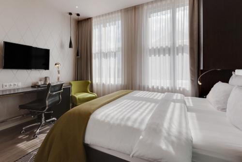 a hotel room with a bed and a desk and a television at Holiday Inn Dresden - Am Zwinger by IHG in Dresden