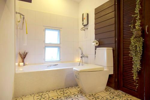 a bathroom with a toilet and a bath tub at Tolani Southgate Villa Chiang Mai in Chiang Mai