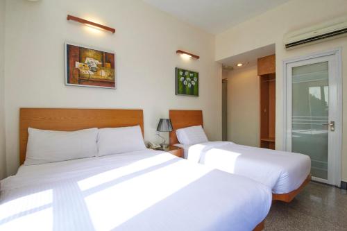 two beds in a hotel room with white sheets at Kepong Hotel in Kuala Lumpur