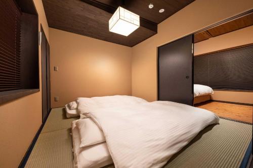 um quarto com uma grande cama branca e um espelho em Tsumugi Horikawarokkaku em Quioto