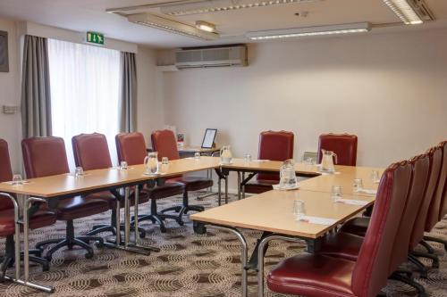a conference room with tables and chairs and a screen at Holiday Inn Lincoln by IHG in Lincoln