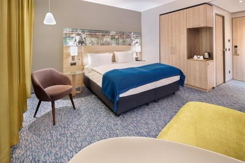 a hotel room with a bed and a chair at Holiday Inn Düsseldorf City – Toulouser Allee by IHG in Düsseldorf