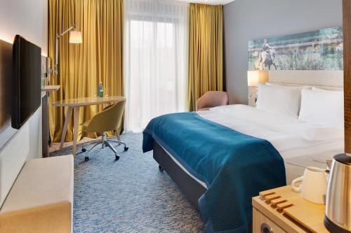 a hotel room with a bed and a desk at Holiday Inn Düsseldorf City – Toulouser Allee by IHG in Düsseldorf